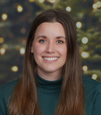 Mallory Moon, vertical photo. She has long brown hair and is wearing a dark green turtleneck.