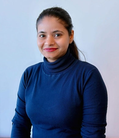 Monika Yadav. Her dark hair is pulled back into a ponytail. She is wearing a navy blue turtleneck.