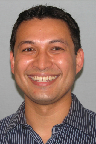 David Williams. He has dark short hair and is wearing a black and white vertically stripped shirt with a collar.